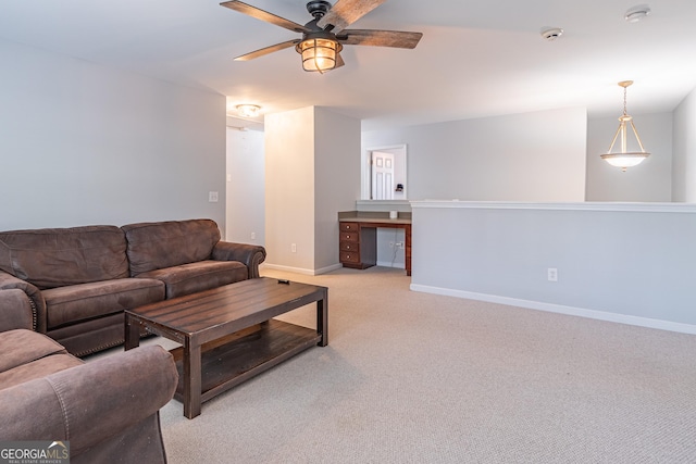 carpeted living room with built in desk and ceiling fan