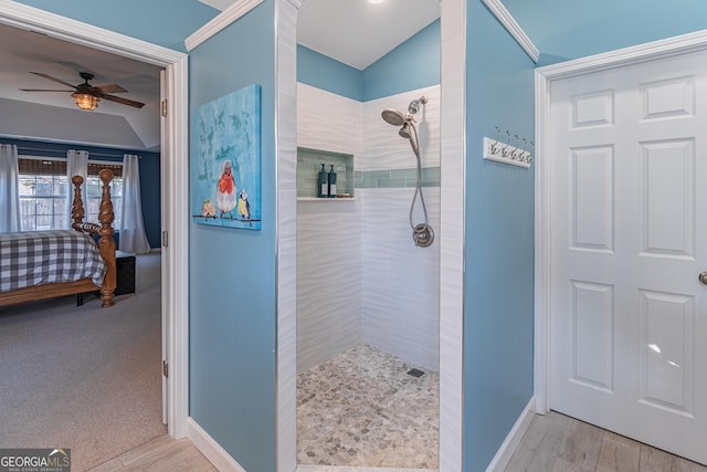 bathroom with ceiling fan, hardwood / wood-style floors, tiled shower, and vaulted ceiling