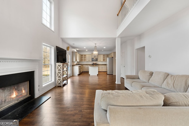 living room featuring sink, dark wood-type flooring, and a towering ceiling