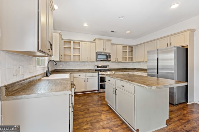 kitchen featuring dark hardwood / wood-style floors, a kitchen island, appliances with stainless steel finishes, cream cabinetry, and sink