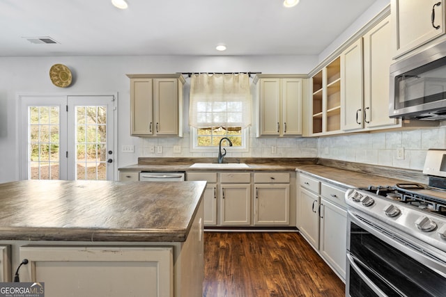 kitchen with appliances with stainless steel finishes, cream cabinetry, backsplash, and sink