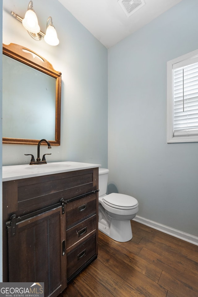 bathroom featuring toilet, wood-type flooring, and vanity