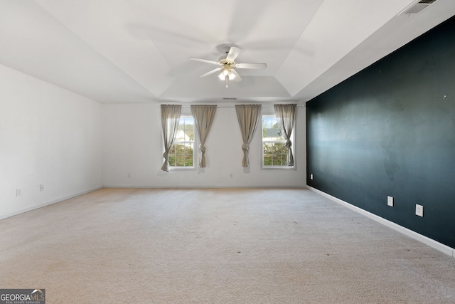 carpeted empty room with ceiling fan and a tray ceiling