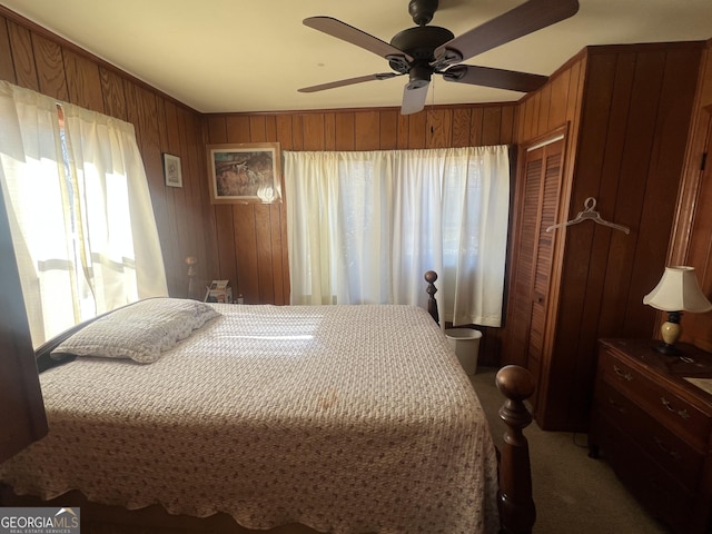 bedroom with carpet floors, a closet, ceiling fan, and wood walls