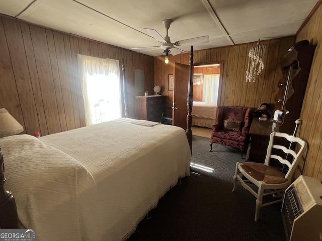 bedroom featuring ceiling fan, wood walls, and carpet