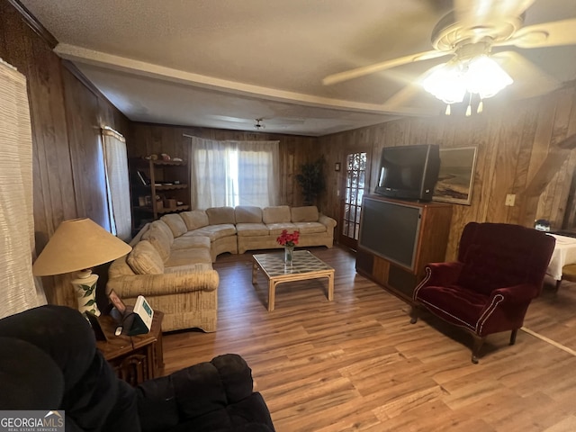 living room featuring ceiling fan, wood walls, and light hardwood / wood-style floors