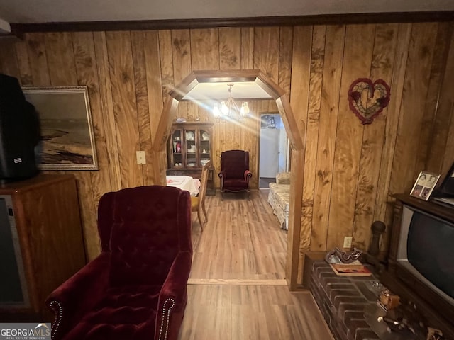 sitting room featuring wood walls, a chandelier, and light hardwood / wood-style flooring