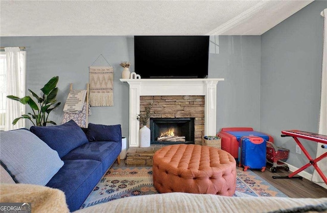 living room featuring a textured ceiling, a stone fireplace, and hardwood / wood-style flooring