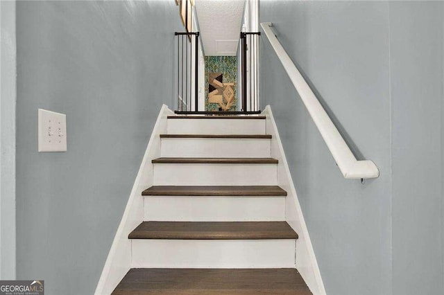 stairway featuring a textured ceiling