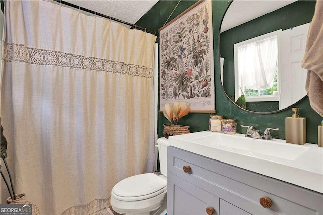 bathroom with a textured ceiling, vanity, and toilet