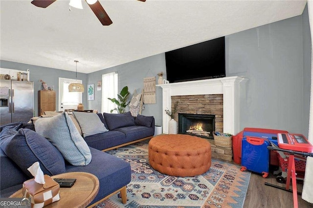 living room featuring wood-type flooring, a fireplace, and ceiling fan