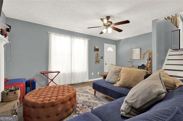 living room featuring ceiling fan and a textured ceiling