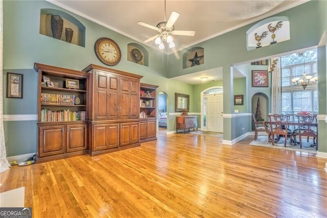 interior space featuring ceiling fan with notable chandelier, a high ceiling, light hardwood / wood-style floors, and crown molding