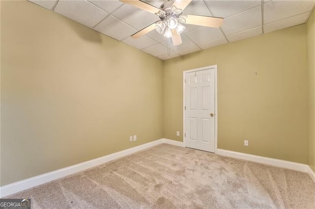 empty room with light carpet, a drop ceiling, and ceiling fan