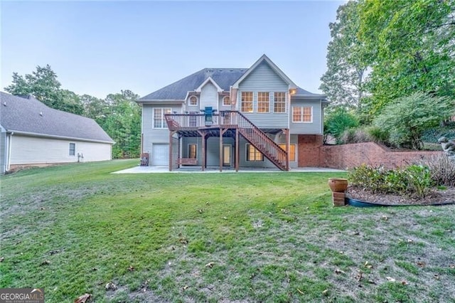 rear view of property featuring a deck, a lawn, and a garage