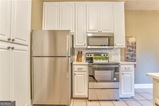 kitchen featuring appliances with stainless steel finishes, light tile patterned floors, and white cabinetry