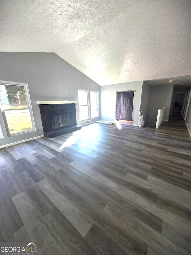 unfurnished living room featuring a textured ceiling, dark wood-type flooring, and vaulted ceiling