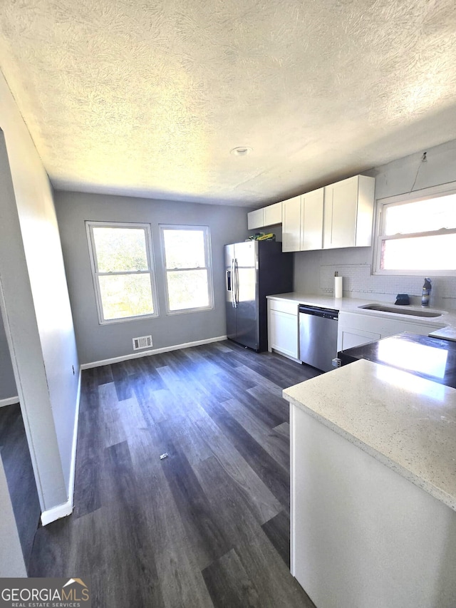 kitchen with sink, white cabinets, dark hardwood / wood-style floors, light stone countertops, and appliances with stainless steel finishes