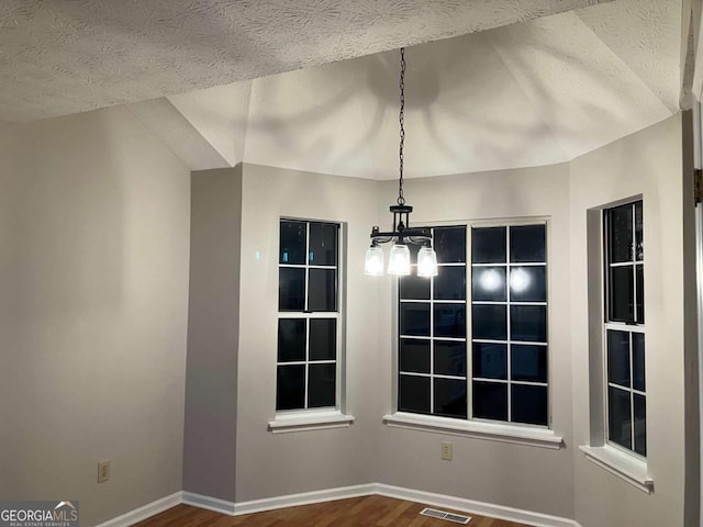 unfurnished dining area with a textured ceiling and wood-type flooring