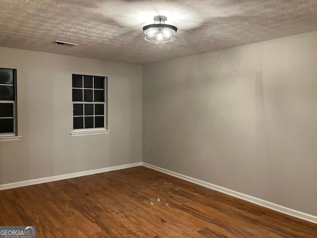 empty room featuring a textured ceiling and hardwood / wood-style floors