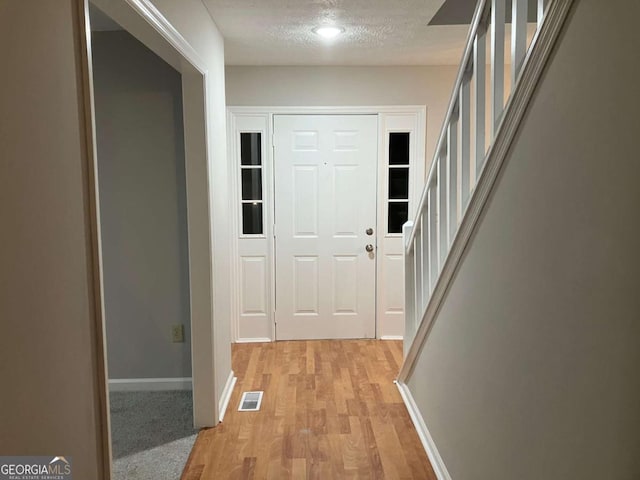 corridor featuring a textured ceiling and light wood-type flooring