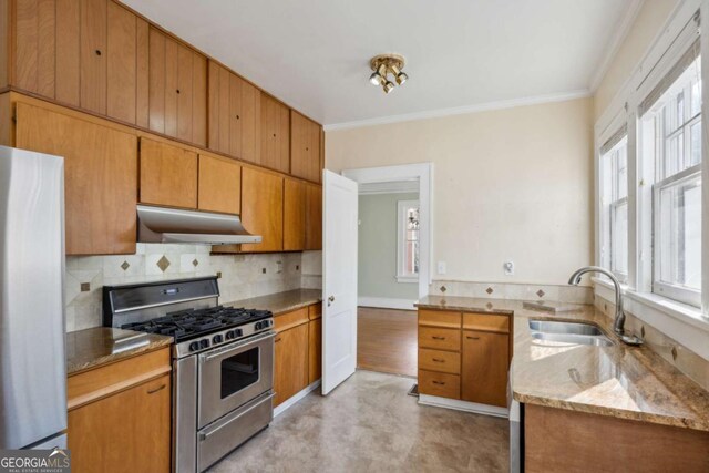 kitchen featuring a sink, decorative backsplash, under cabinet range hood, appliances with stainless steel finishes, and crown molding