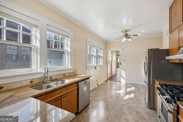 kitchen with baseboards, ornamental molding, a sink, appliances with stainless steel finishes, and brown cabinets