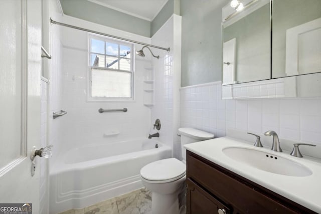 full bath with tub / shower combination, toilet, vanity, wainscoting, and tile walls