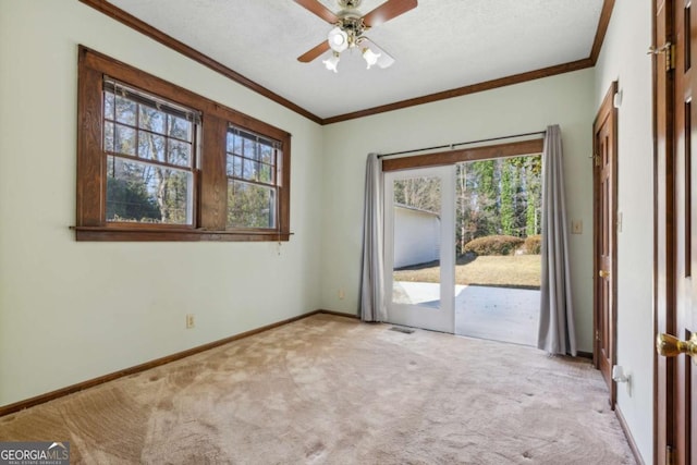 carpeted spare room with plenty of natural light, baseboards, and ornamental molding