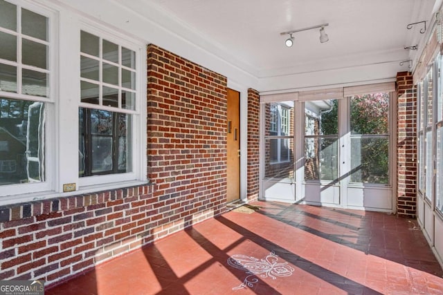 unfurnished sunroom with rail lighting