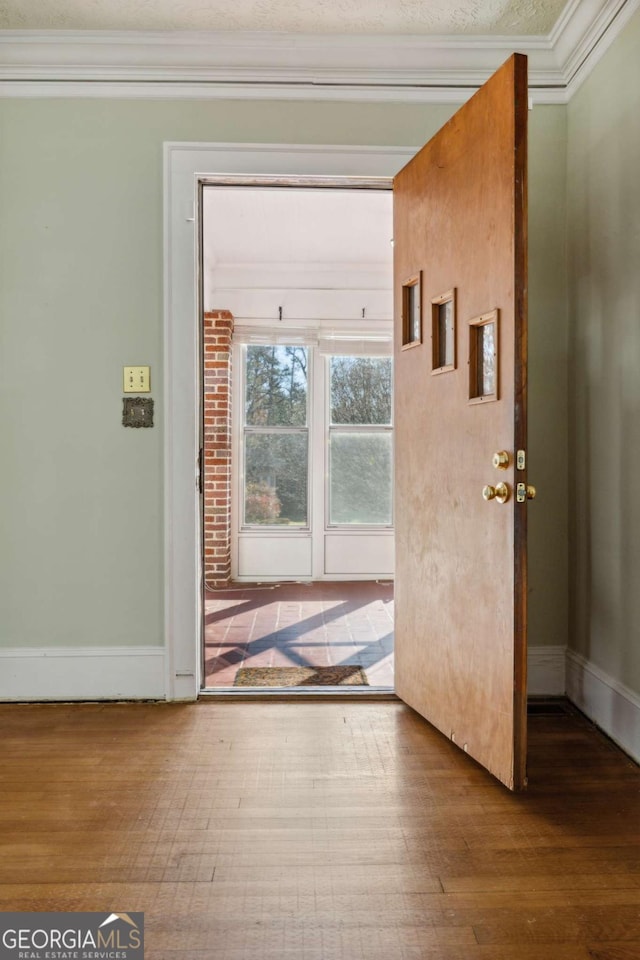 doorway to outside with crown molding, baseboards, and wood finished floors