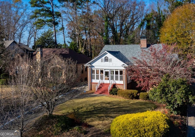 view of front of property featuring a front yard and a sunroom