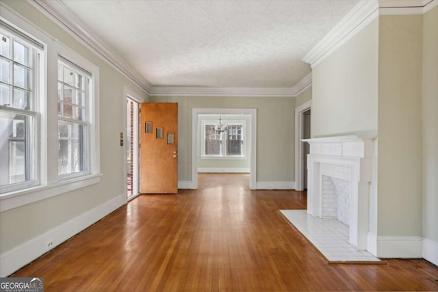 unfurnished living room featuring baseboards, a textured ceiling, wood finished floors, and ornamental molding