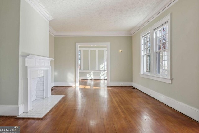 unfurnished living room featuring ornamental molding, a textured ceiling, baseboards, and wood-type flooring