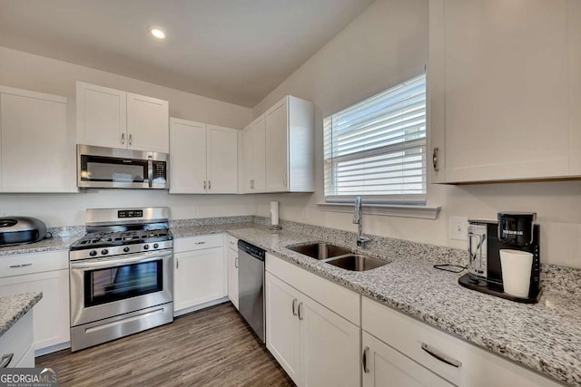 kitchen featuring stainless steel appliances, light stone countertops, white cabinetry, and sink