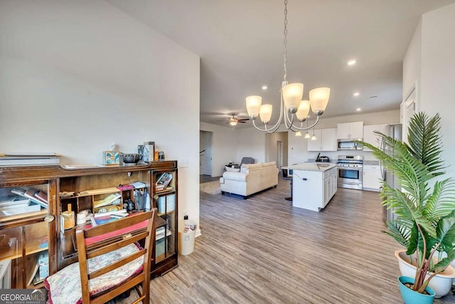 dining space featuring light hardwood / wood-style flooring and ceiling fan with notable chandelier