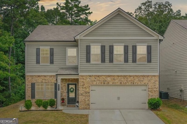 view of front facade with a garage, a yard, and central AC