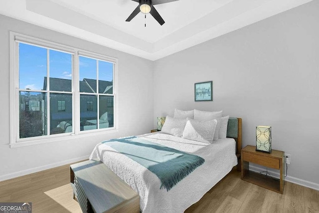 bedroom featuring a tray ceiling, hardwood / wood-style floors, and ceiling fan