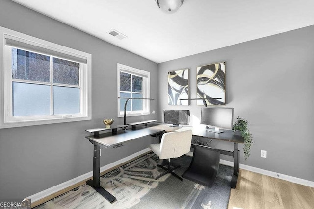 home office with light wood-type flooring and a wealth of natural light