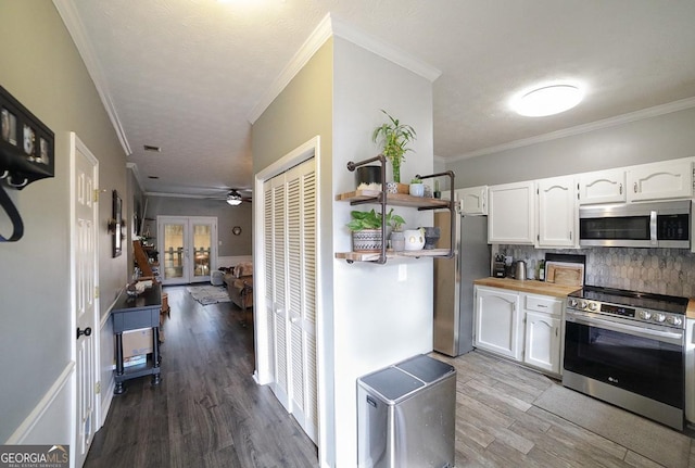 kitchen with stainless steel appliances, white cabinetry, tasteful backsplash, wooden counters, and crown molding