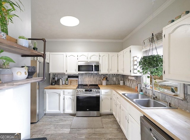 kitchen featuring decorative backsplash, crown molding, white cabinets, appliances with stainless steel finishes, and sink