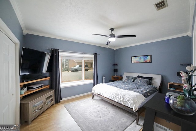 bedroom with ornamental molding, ceiling fan, and light wood-type flooring