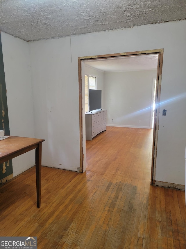 corridor with a textured ceiling and light hardwood / wood-style flooring