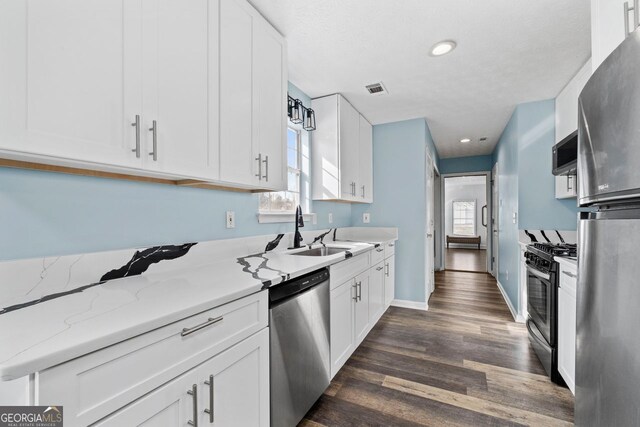 kitchen featuring sink, stainless steel appliances, white cabinets, and light stone counters