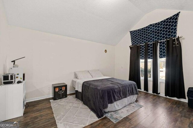 bedroom featuring a textured ceiling, hardwood / wood-style floors, and vaulted ceiling