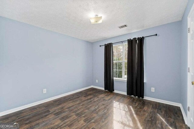 unfurnished room with a textured ceiling and dark hardwood / wood-style floors