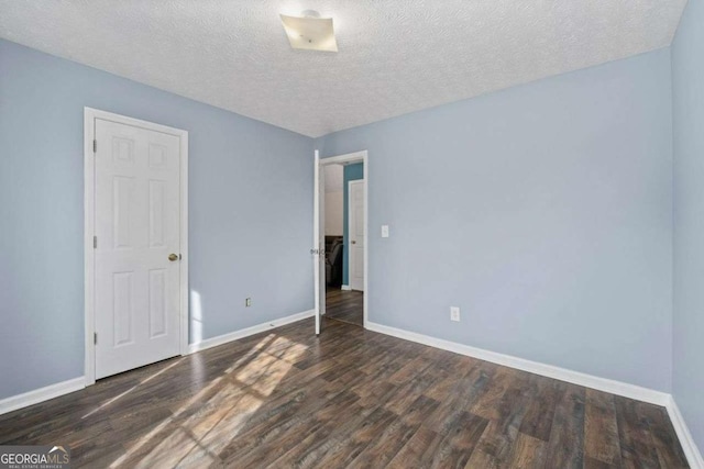 unfurnished bedroom featuring a textured ceiling and dark hardwood / wood-style floors