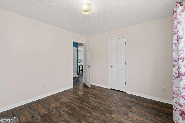 unfurnished room featuring a textured ceiling and dark hardwood / wood-style flooring