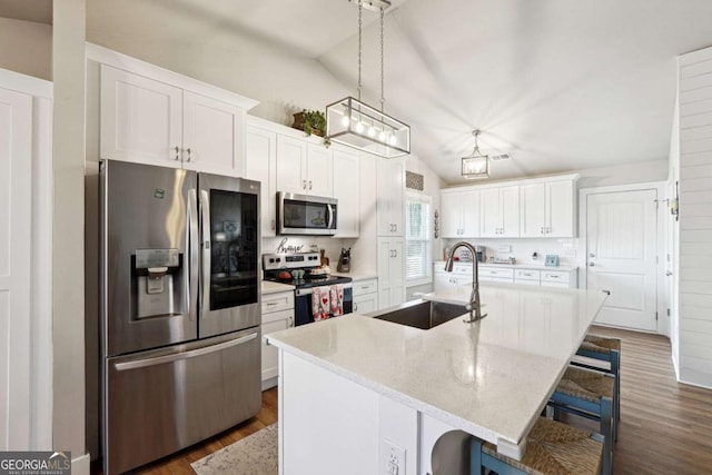 kitchen with white cabinets, a center island with sink, stainless steel appliances, decorative backsplash, and sink