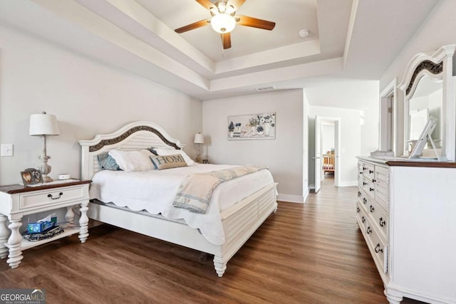 bedroom featuring ceiling fan, a tray ceiling, and dark hardwood / wood-style floors